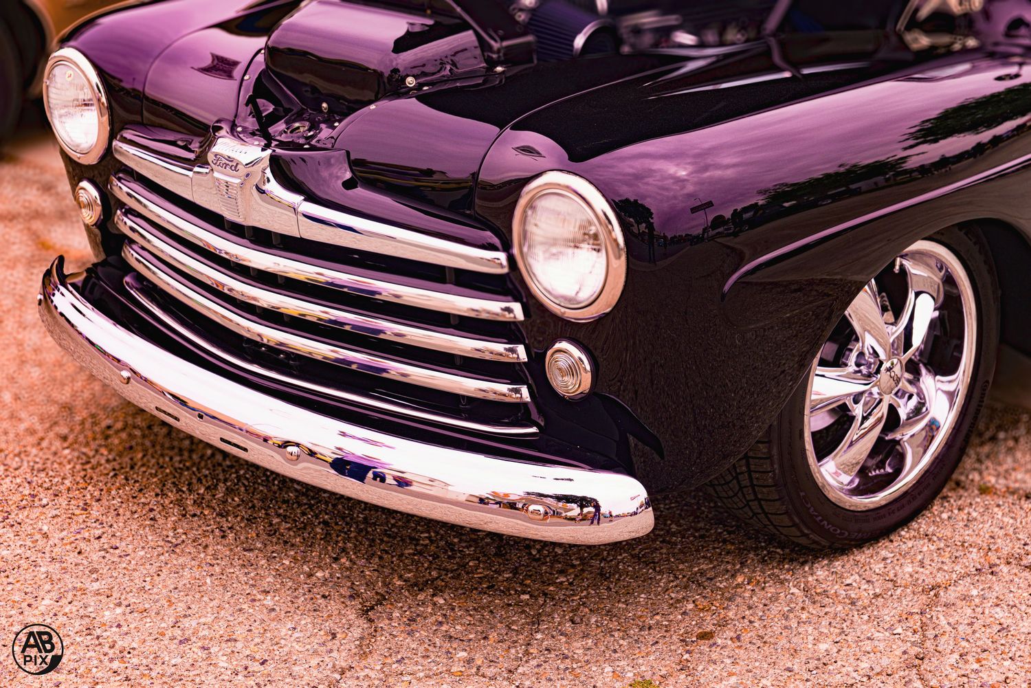 Close-up of a purple classic car front end with chrome grille and custom alloy wheels.