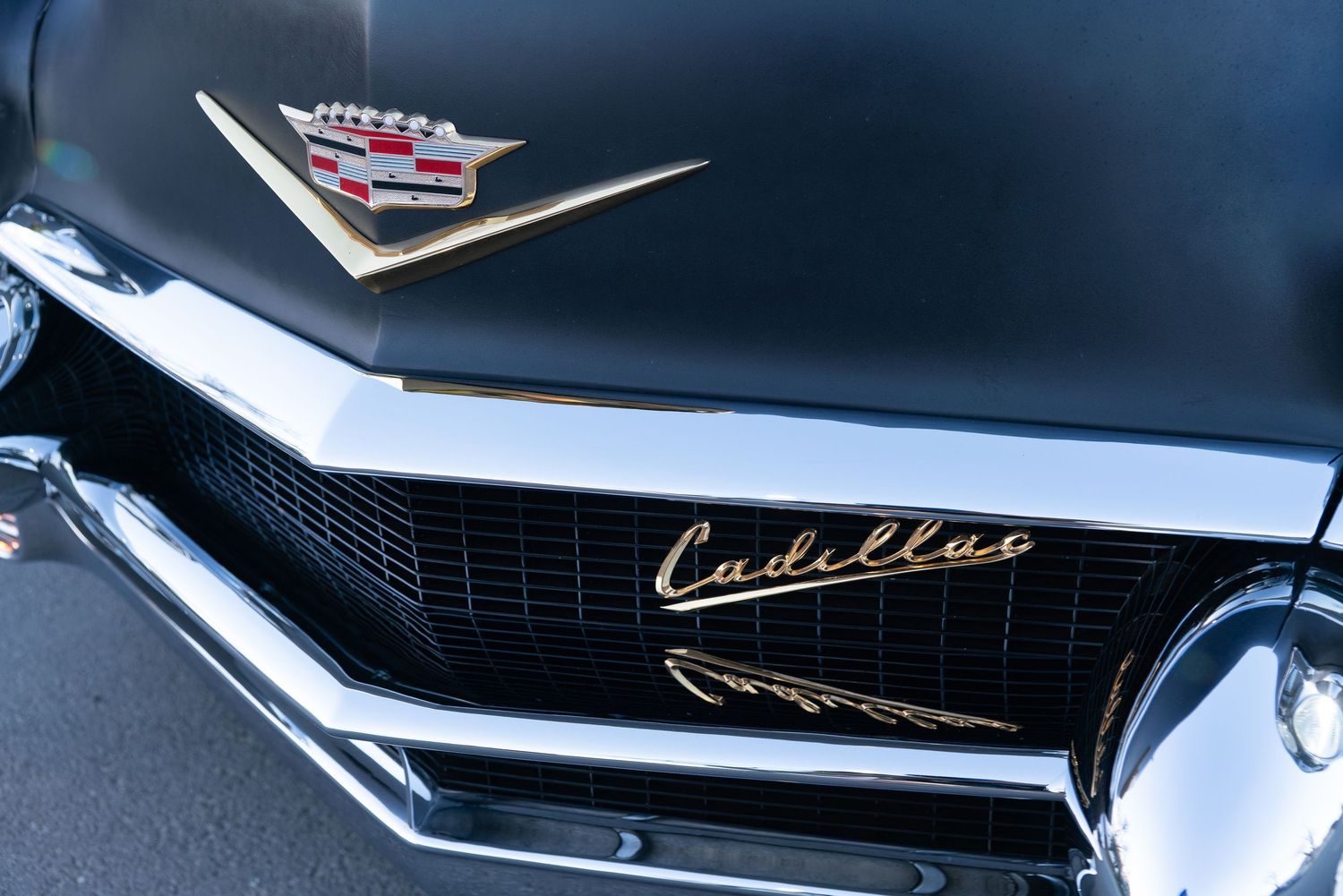 Close-up of a classic black Cadillac car hood ornament and chrome grille badge.