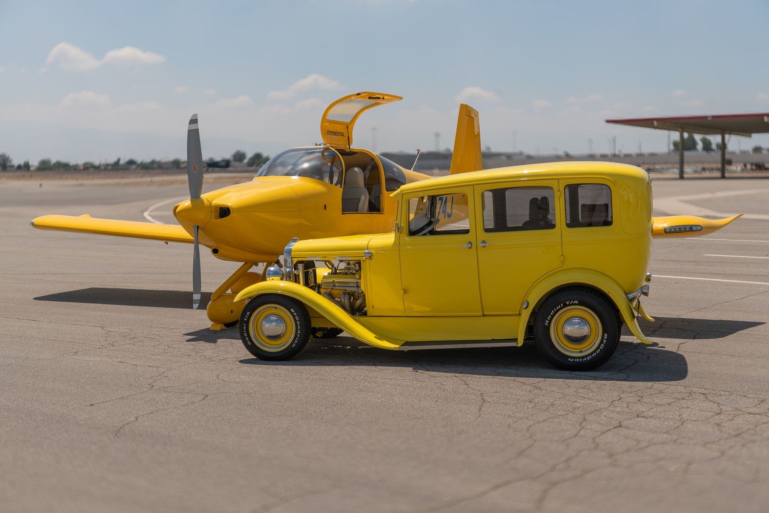 Unique yellow hot rod car combined with a small yellow airplane on an airport tarmac.