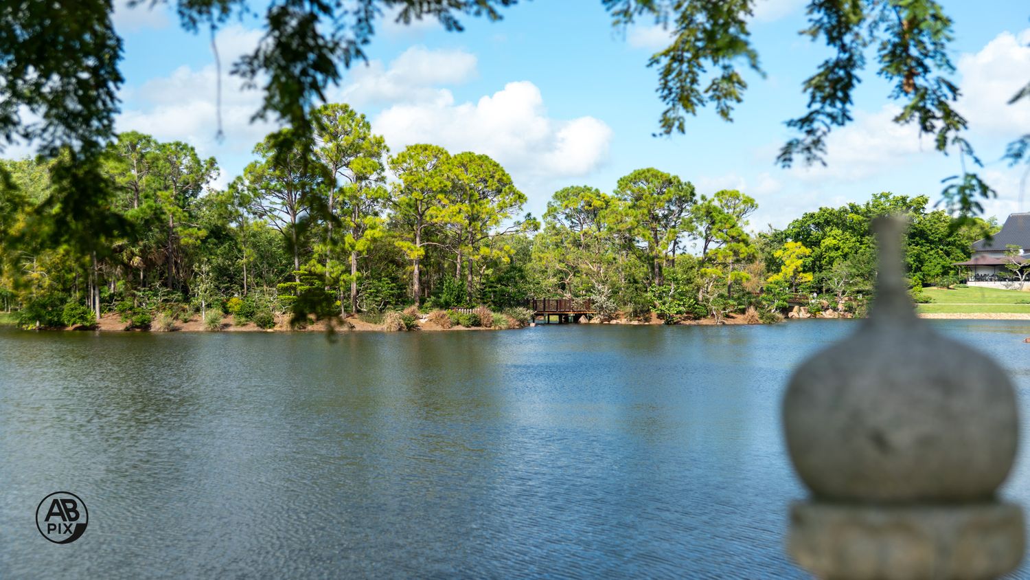 Stone ornament foreground with a serene blue lake and lush trees beyond.