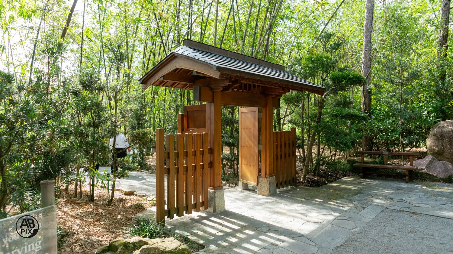 Traditional Japanese wooden gate entrance surrounded by bamboo and lush greenery in a zen garden.
