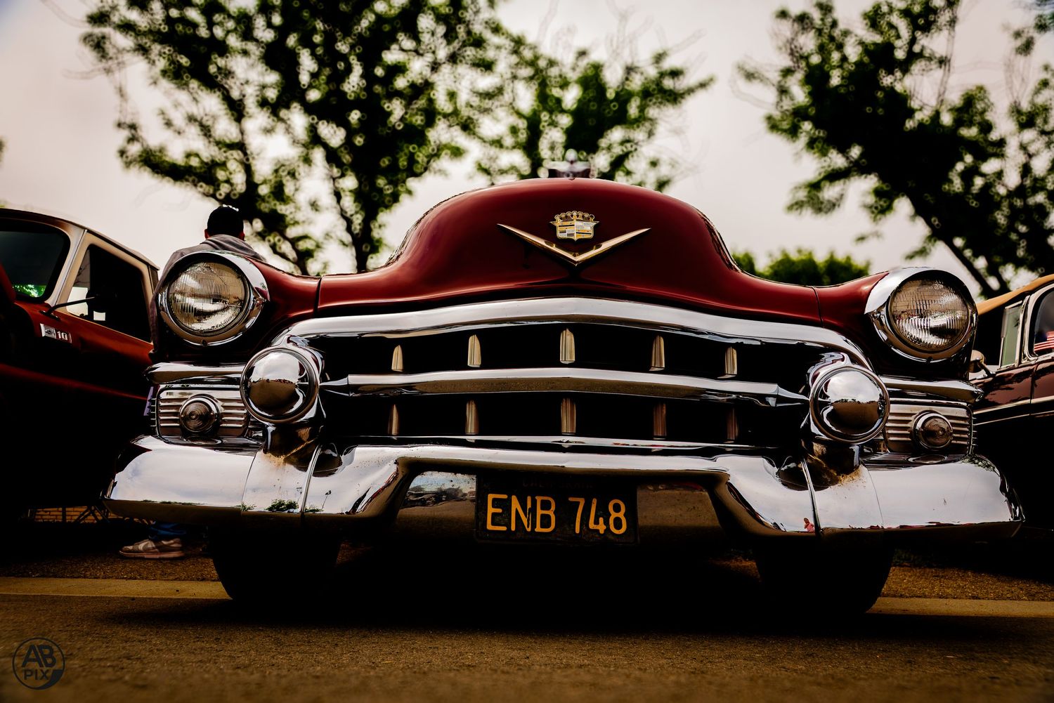 Low-angle front view of a red classic Cadillac with chrome grille and plate ENB 748.