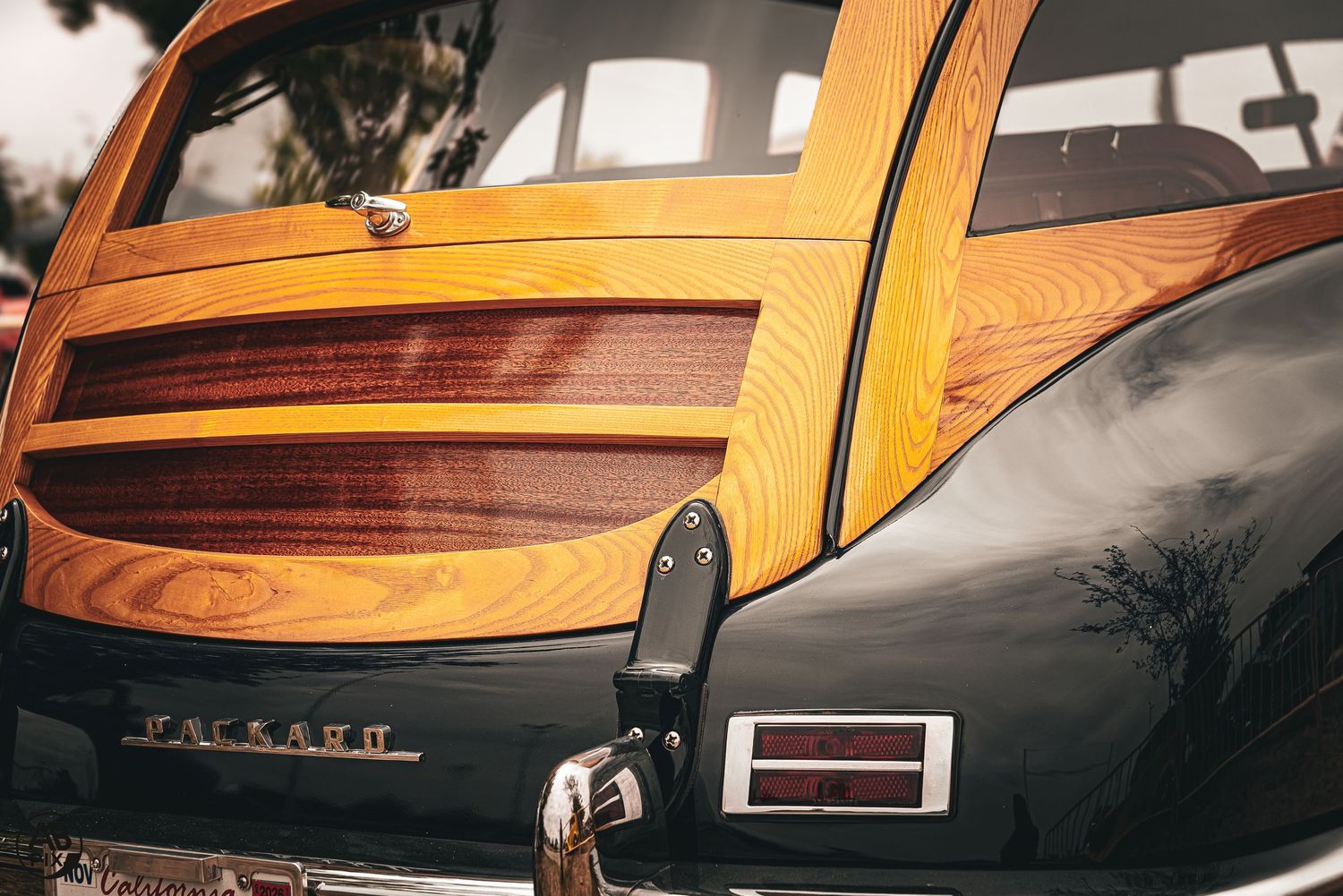 Close-up of a classic Packard car featuring elegant wood panel detailing on its dark body.