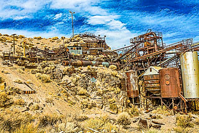 Colorful HDR photo of an abandoned desert mining facility with rusty industrial equipment and machinery.