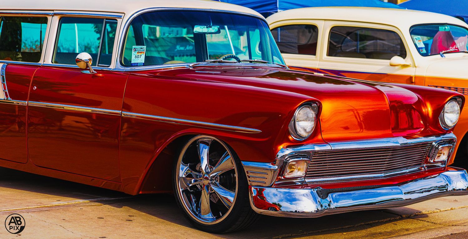 Red and white classic 1956 Chevrolet Nomad wagon custom at outdoor car show.