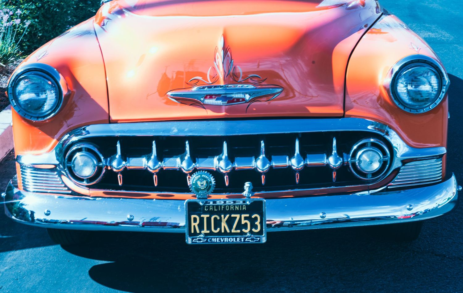Front view of a vintage orange Chevrolet classic car with chrome grille and RICKZ53 license plate.