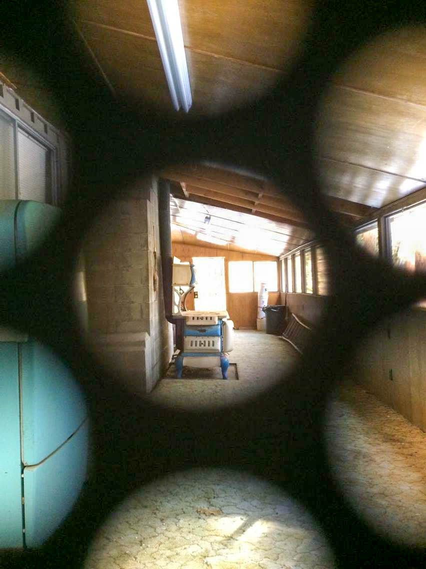Interior of an old wooden workshop viewed through circular pipe openings with fluorescent lighting.