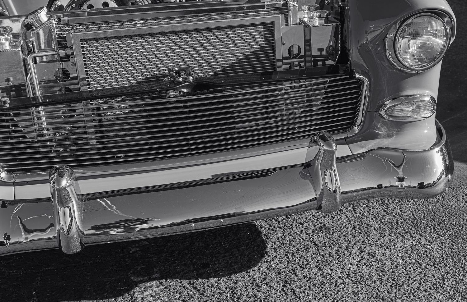 Black and white photo of a classic vintage car front bumper and grille, showcasing chrome details and retro automotive design.