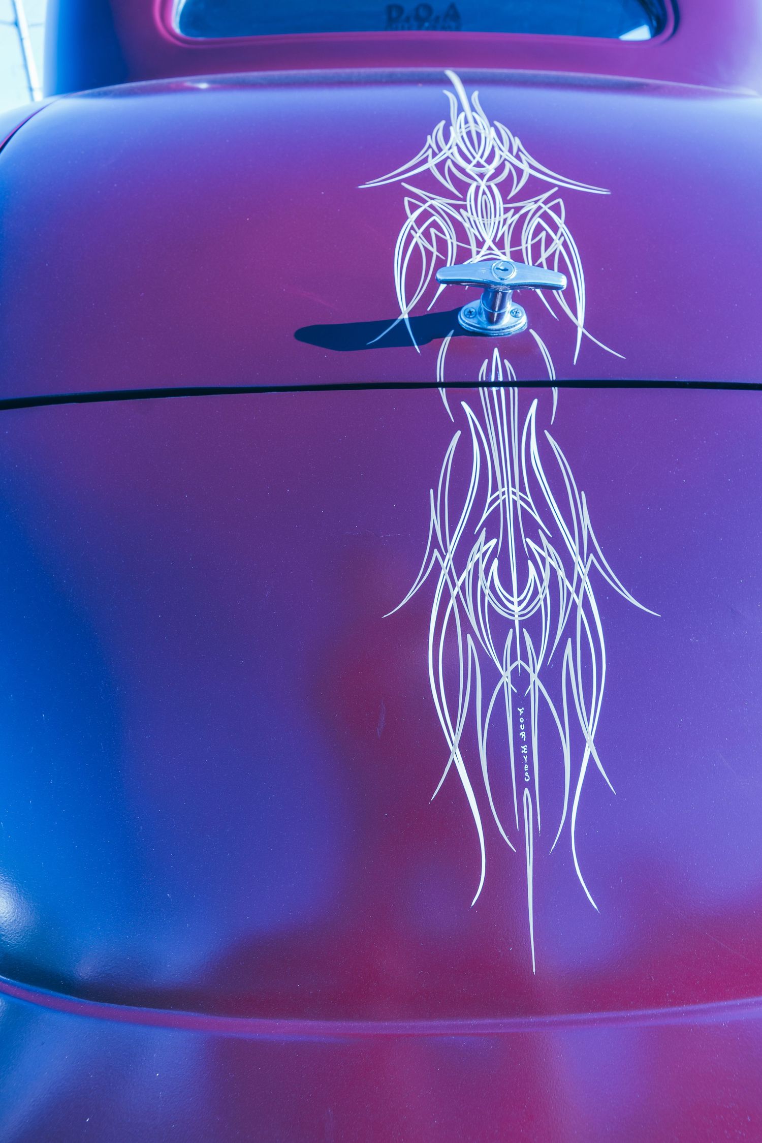 Purple custom classic car hood with intricate white pinstripe tribal art design and hood pin.