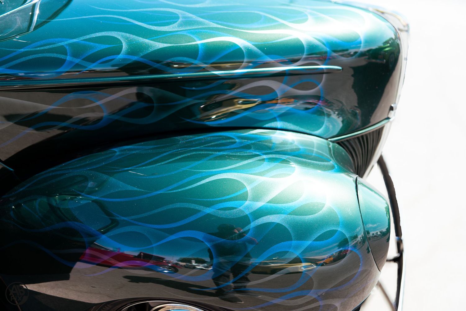 Close-up of teal and black custom car paint with blue flame airbrushed design.