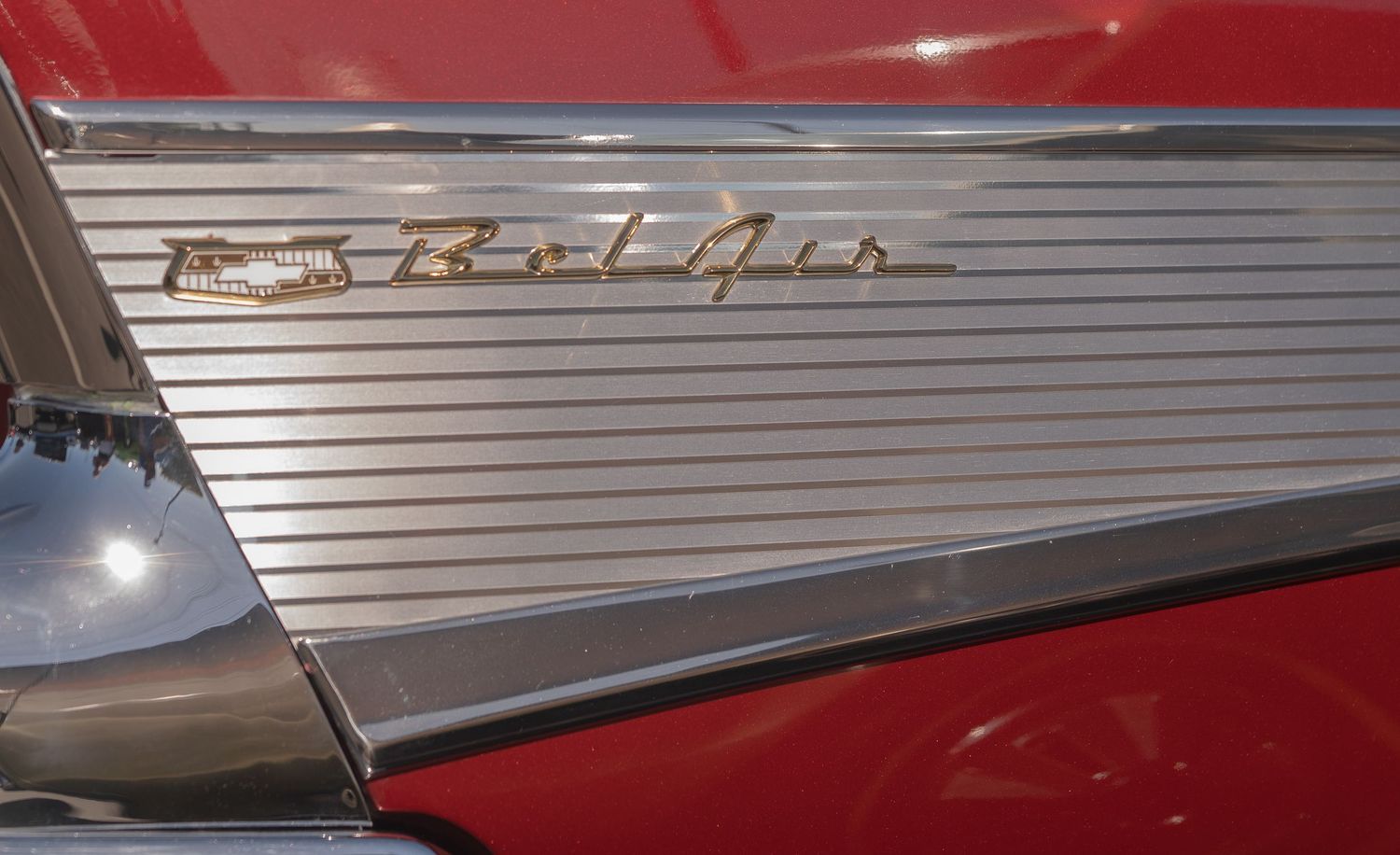Close-up of a classic red Chevrolet Bel Air chrome emblem and fin detail on a vintage American car.
