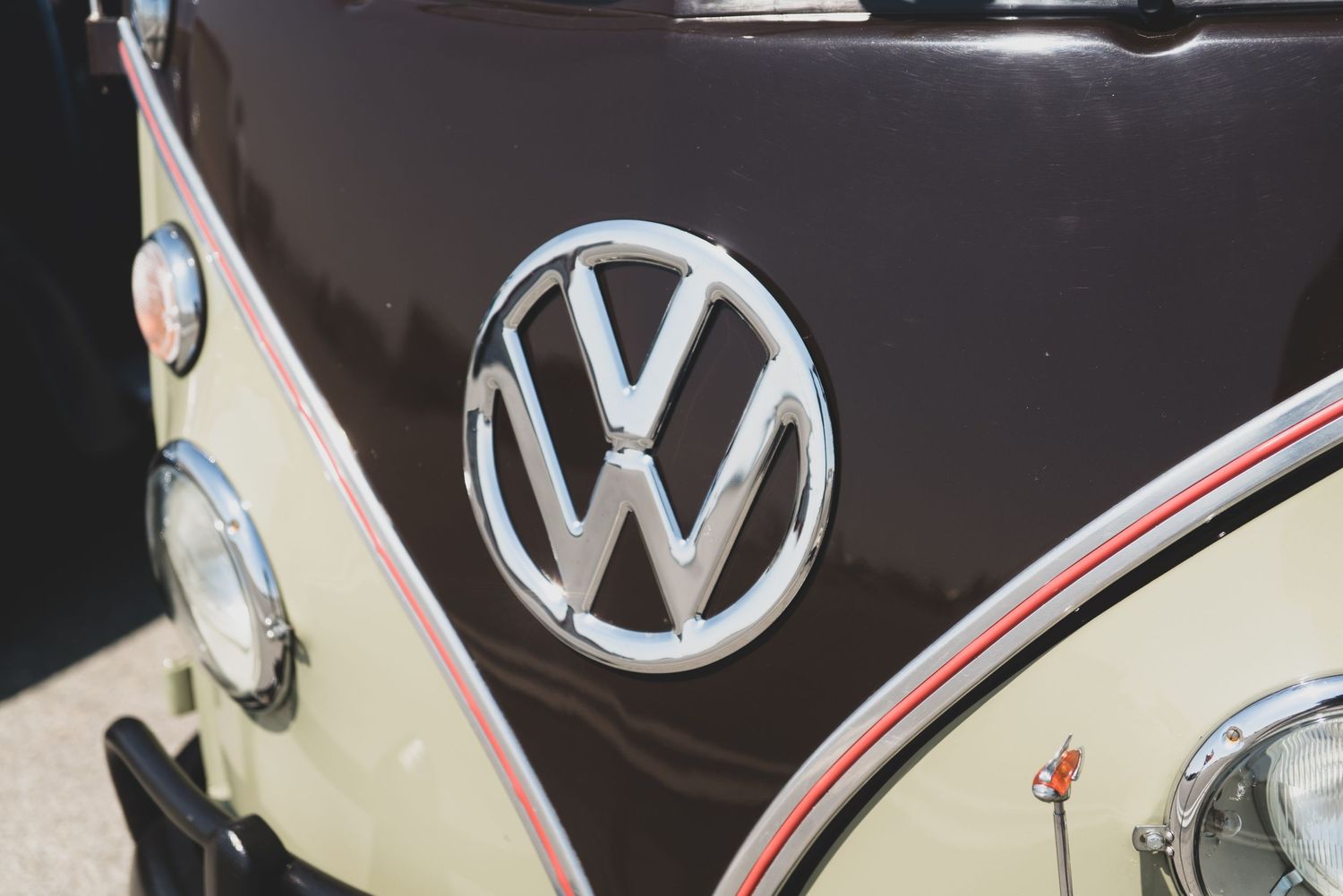 Close-up of a chrome VW Volkswagen logo emblem on a classic vintage black and cream colored van.
