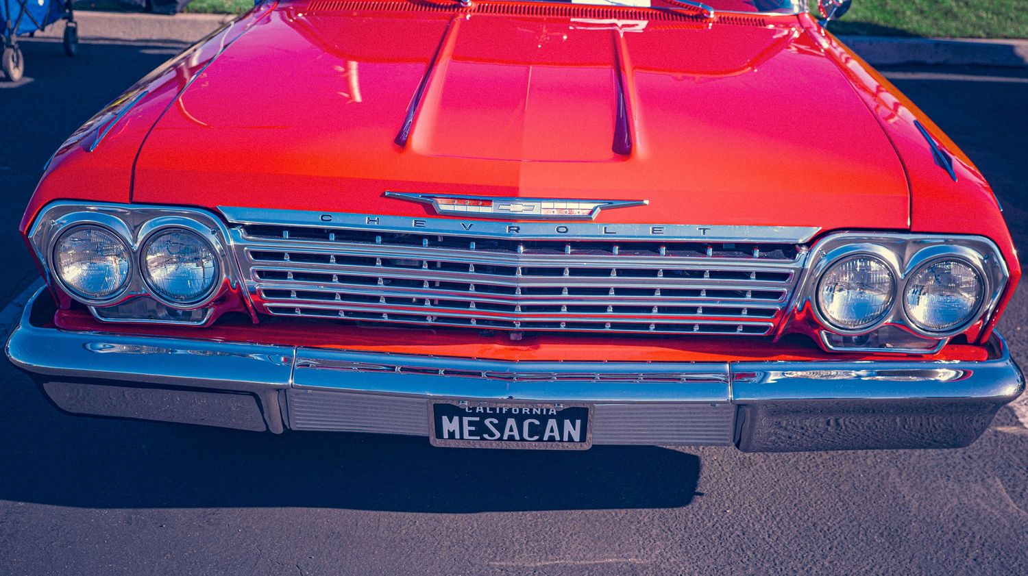 Red 1962 Chevrolet Impala classic car with chrome grille and MESACAN license plate at outdoor car show.