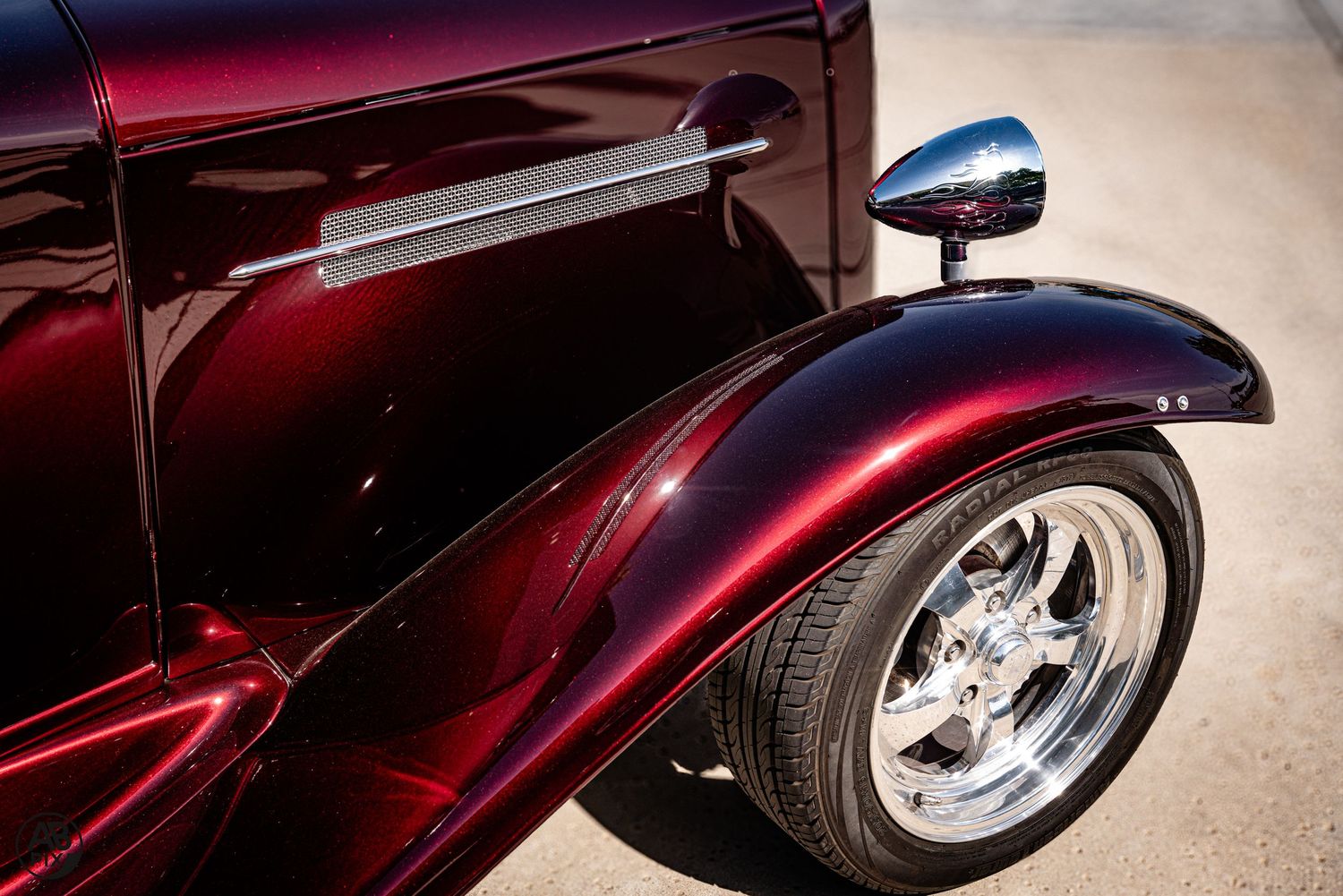 Deep red candy paint classic hot rod with chrome wheel and mirror detail.