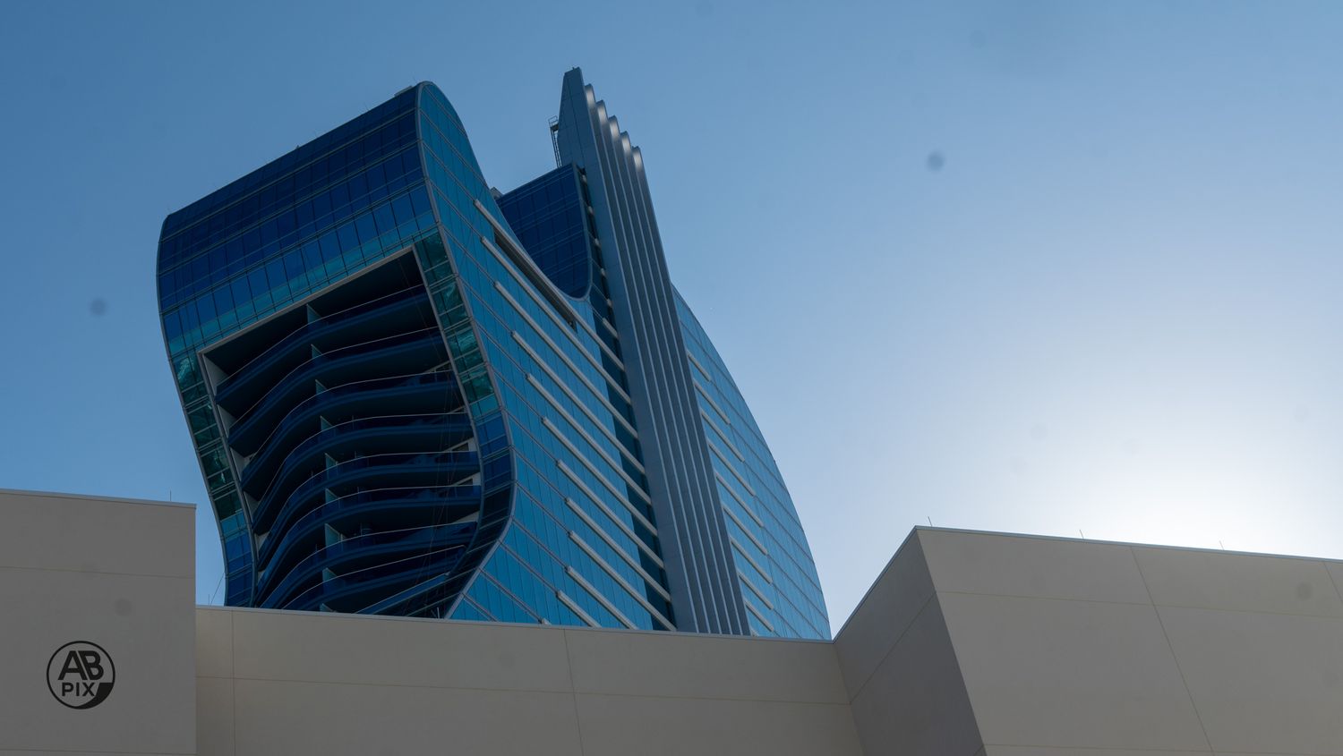Modern twisted glass skyscraper against clear blue sky viewed from below.