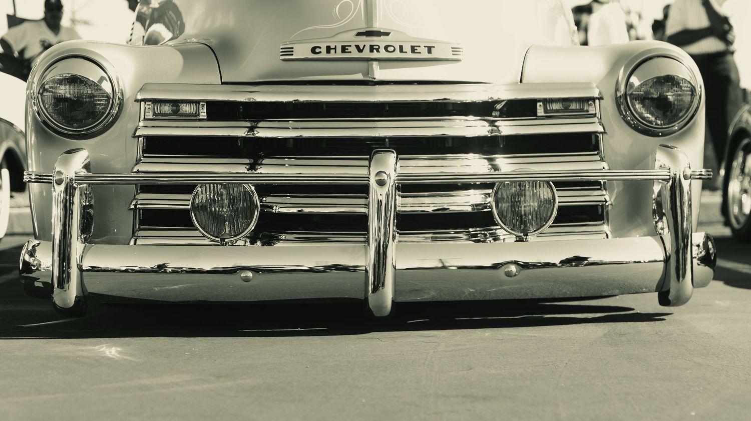 Vintage Chevrolet truck front grille and bumper in black and white photo.