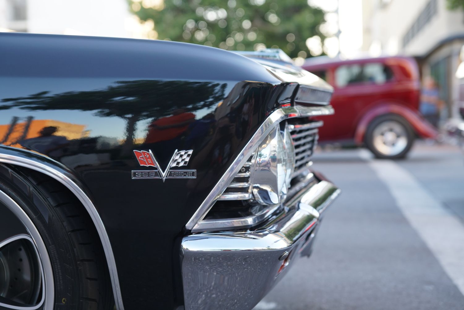 Close-up of a black Chevrolet Corvette badge and chrome trim at an outdoor car show.