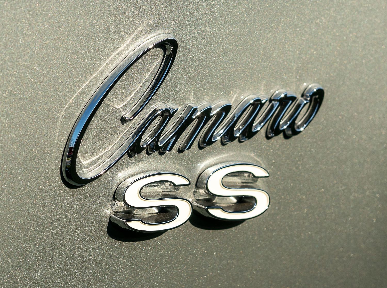 Close-up of chrome Camaro SS emblem badge on classic muscle car body panel.
