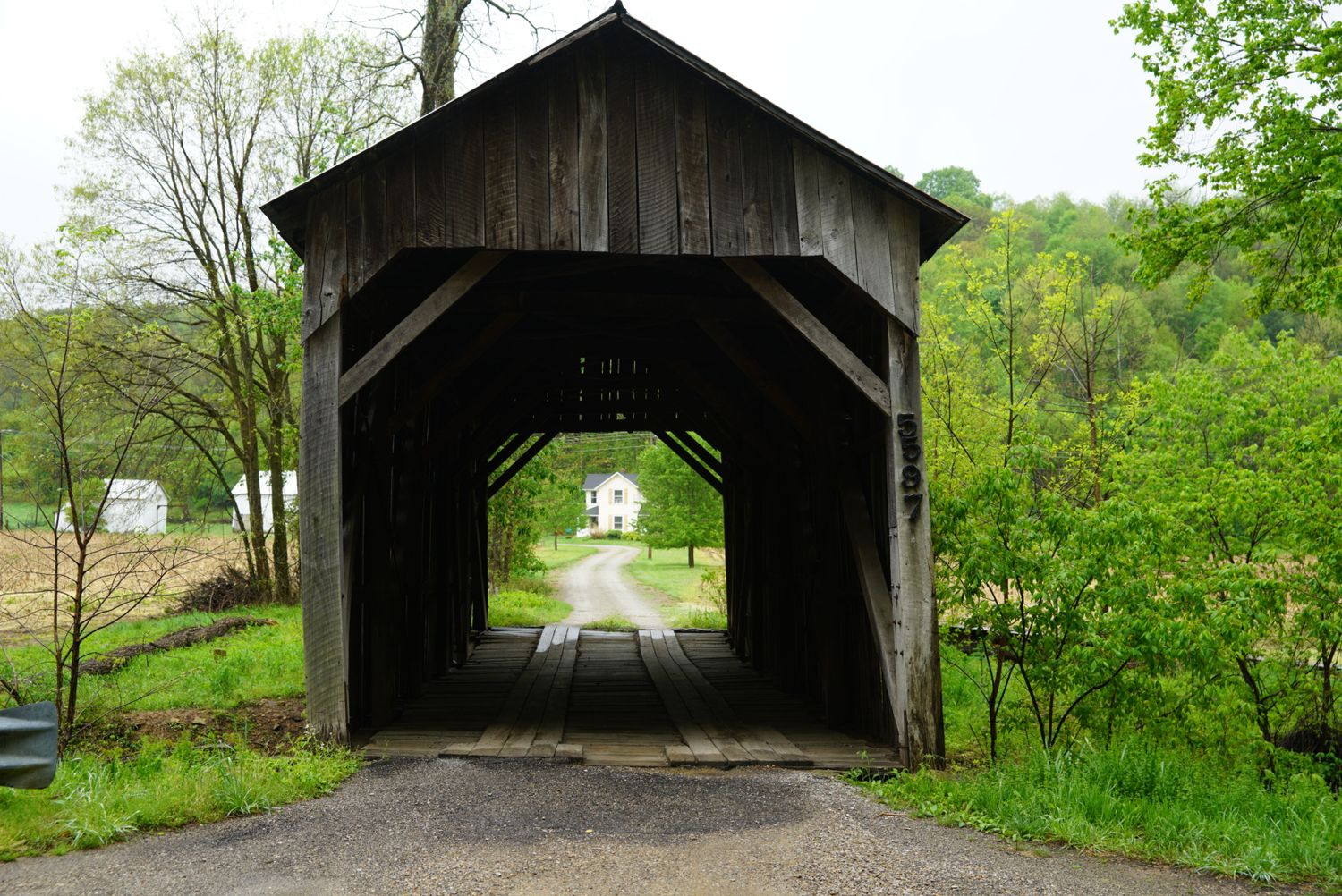Historic wooden covered bridge framing a white country church on a rural road in Ohio.