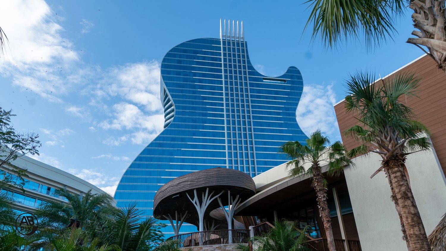 Iconic guitar-shaped blue glass hotel building at Seminole Hard Rock Hollywood Florida against blue sky.