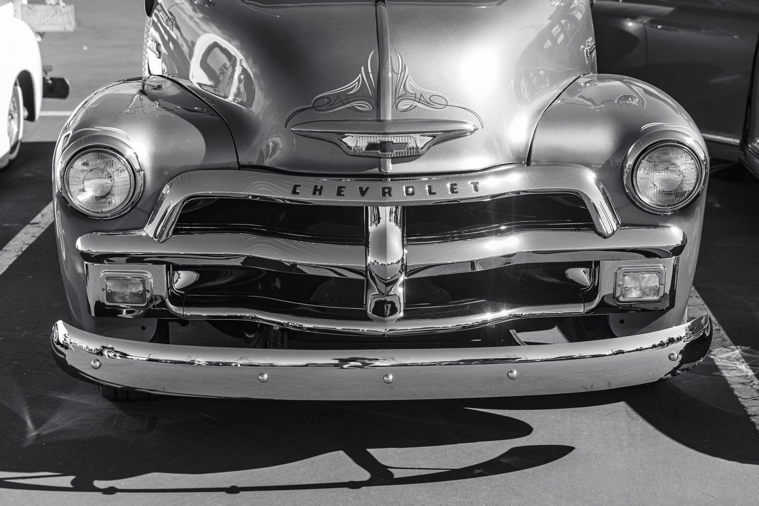 Black and white photo of a classic vintage Chevrolet car, showcasing its chrome bumper and iconic front grille design.