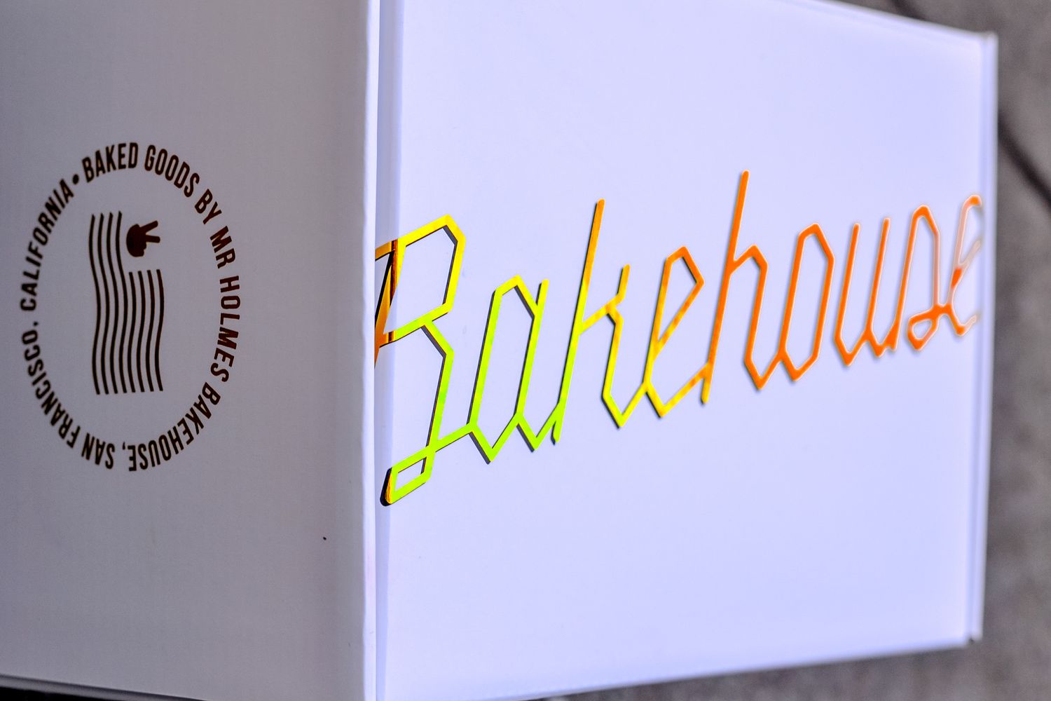 Colorful neon sign for Bakehouse, a San Francisco California baked goods shop, glowing in yellow, orange, and green.
