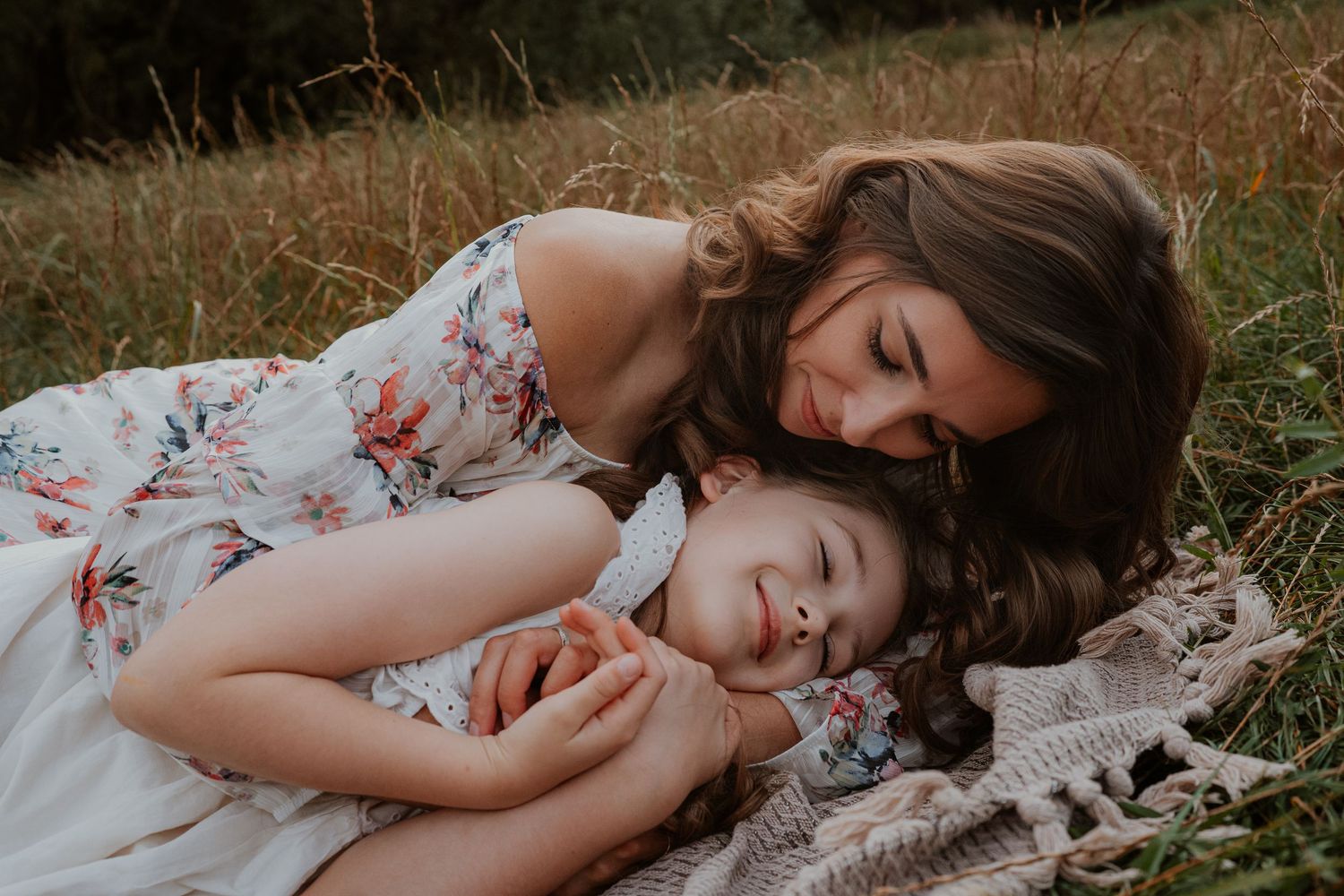 A person lying peacefully in a grassy field wearing a floral dress.