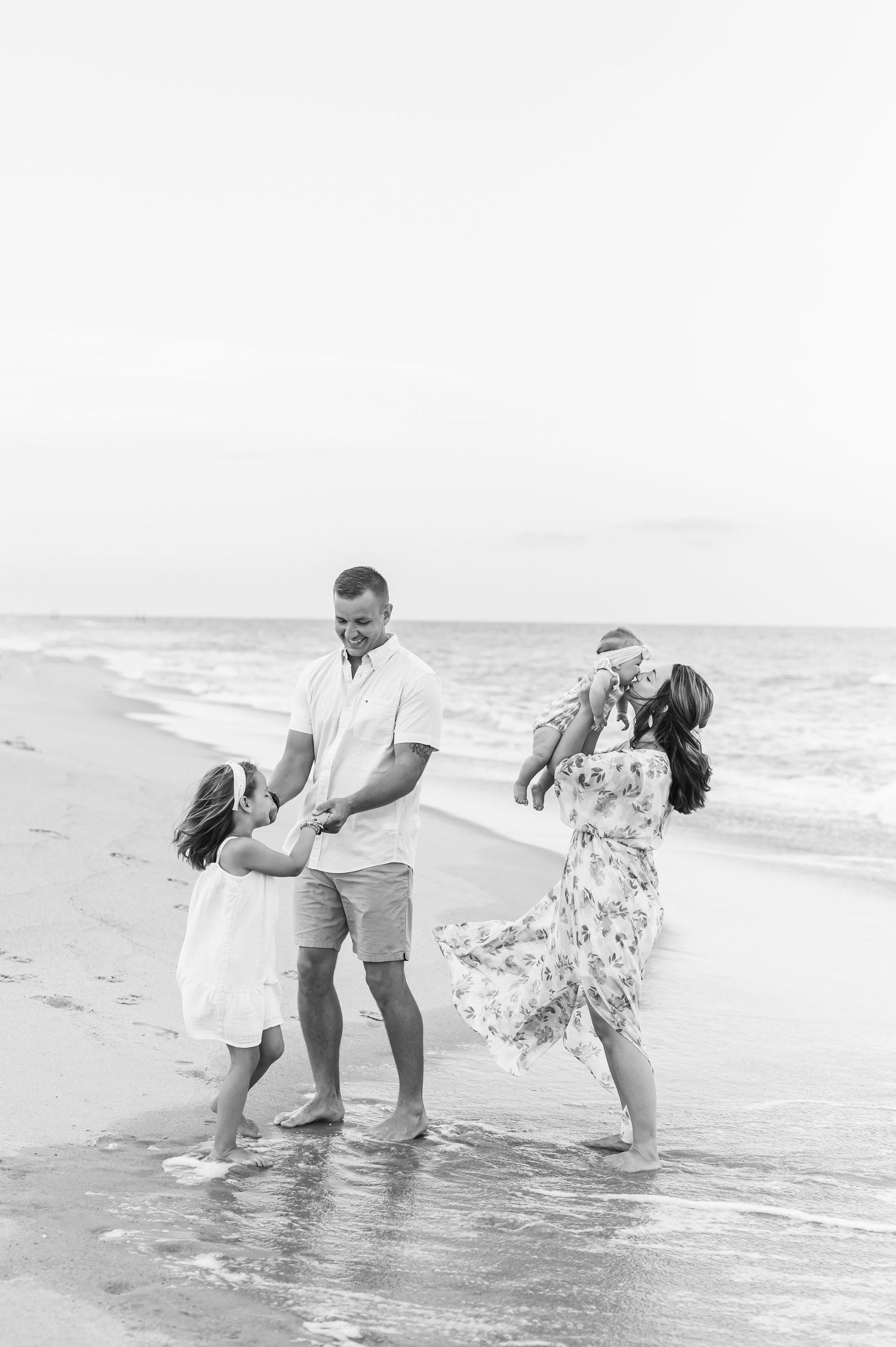A couple plays and splashes together at the beach in a series of black and white romantic photos.