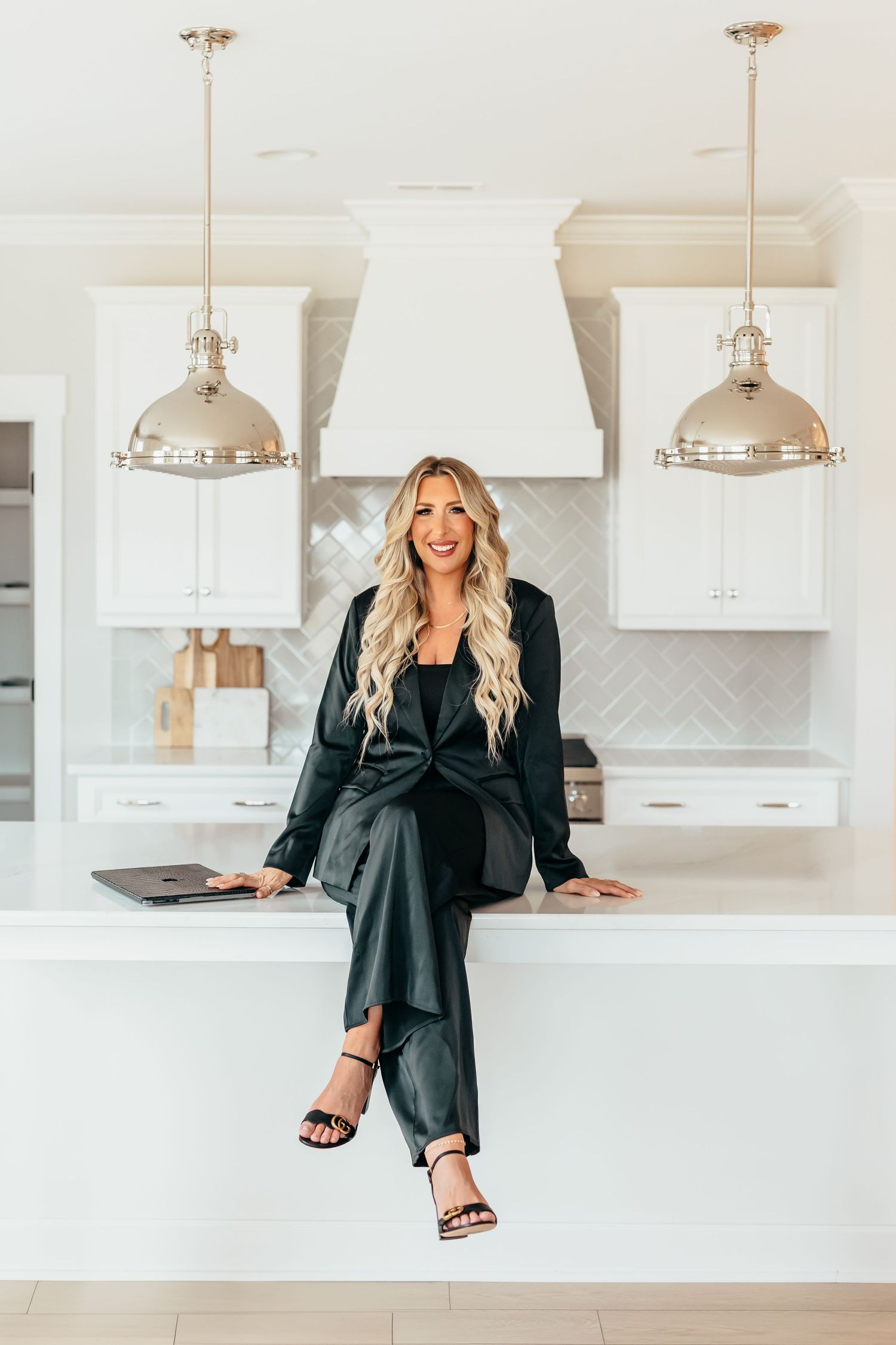Modern white kitchen interior with pendant lights and black accent decor showcases sleek contemporary design elements.