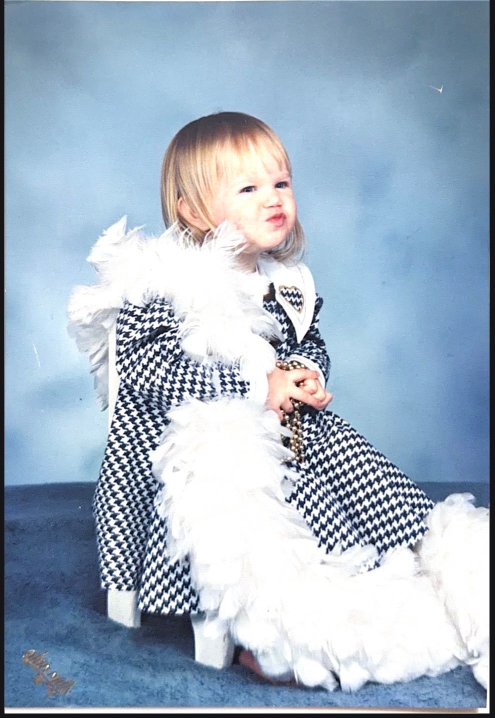 A series of four photos showing someone in a black and white checkered outfit with white feather accents against a blue backdrop.