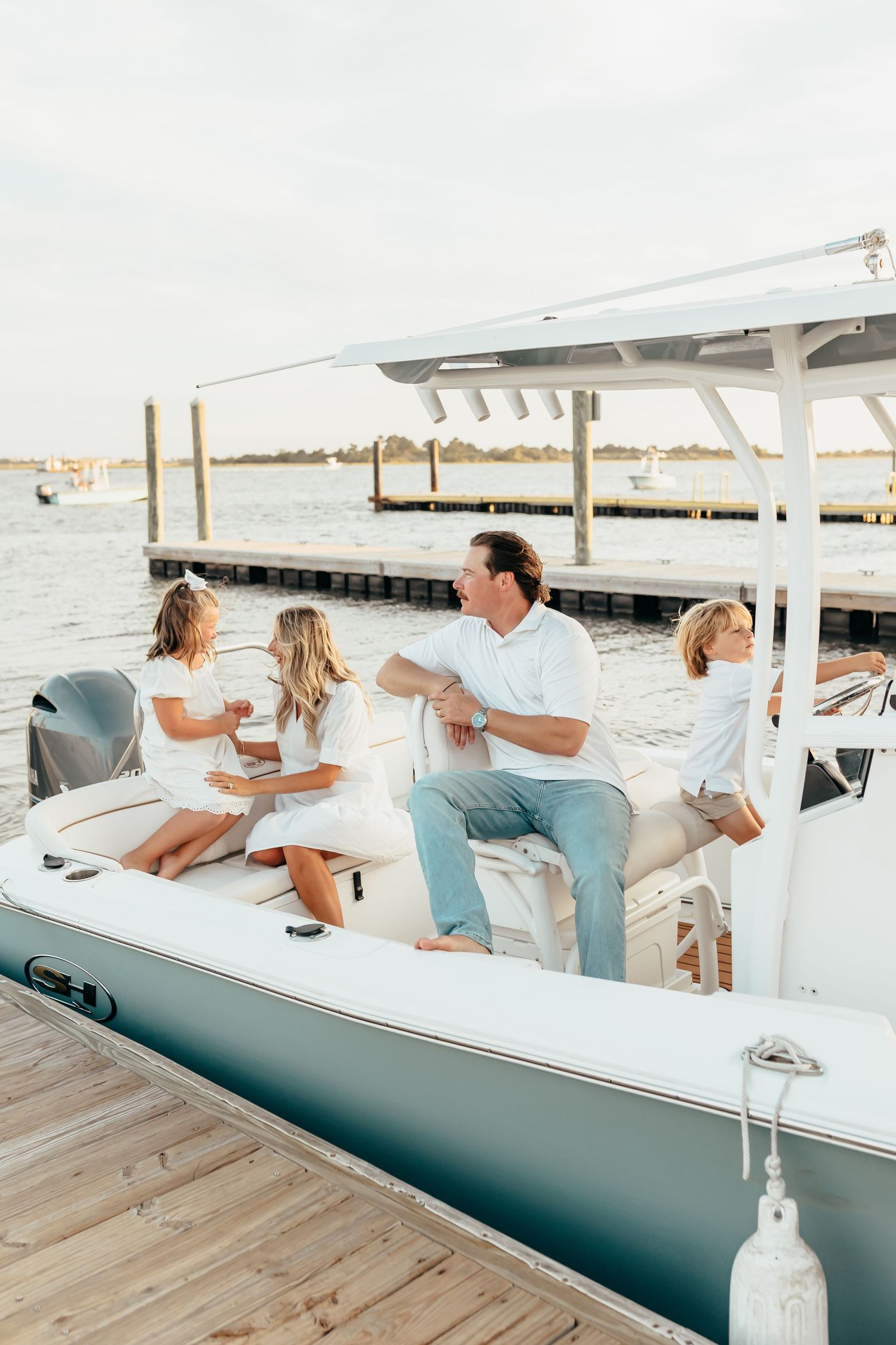 A group of people enjoying a sunny day on a white boat dock by the water.
