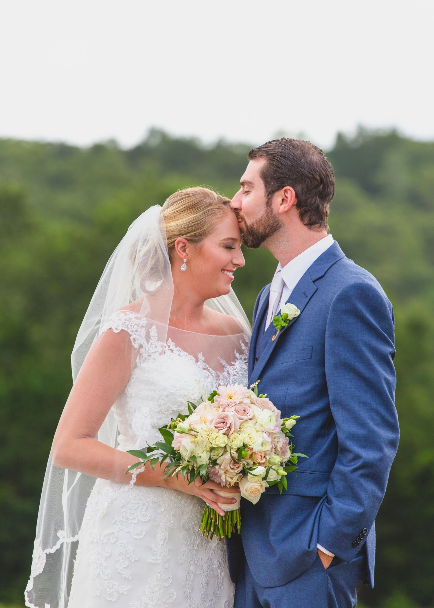 Intimate wedding moment captured outdoors with greenery backdrop.