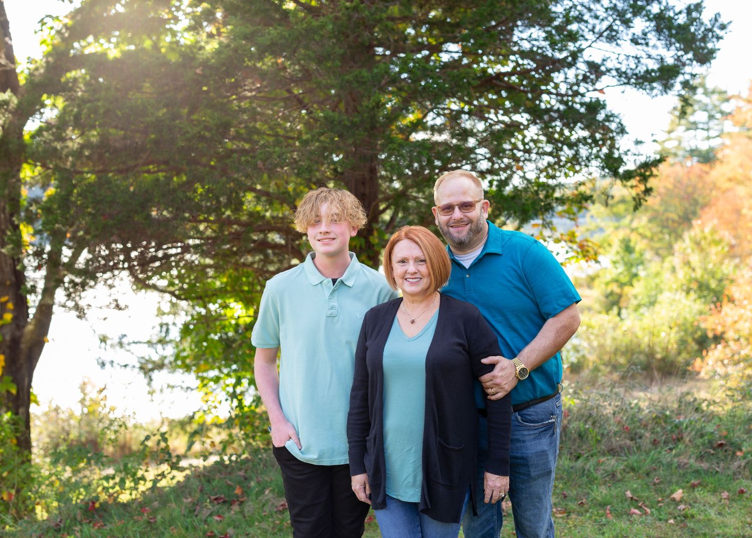 Family smiling together in outdoor autumn setting.