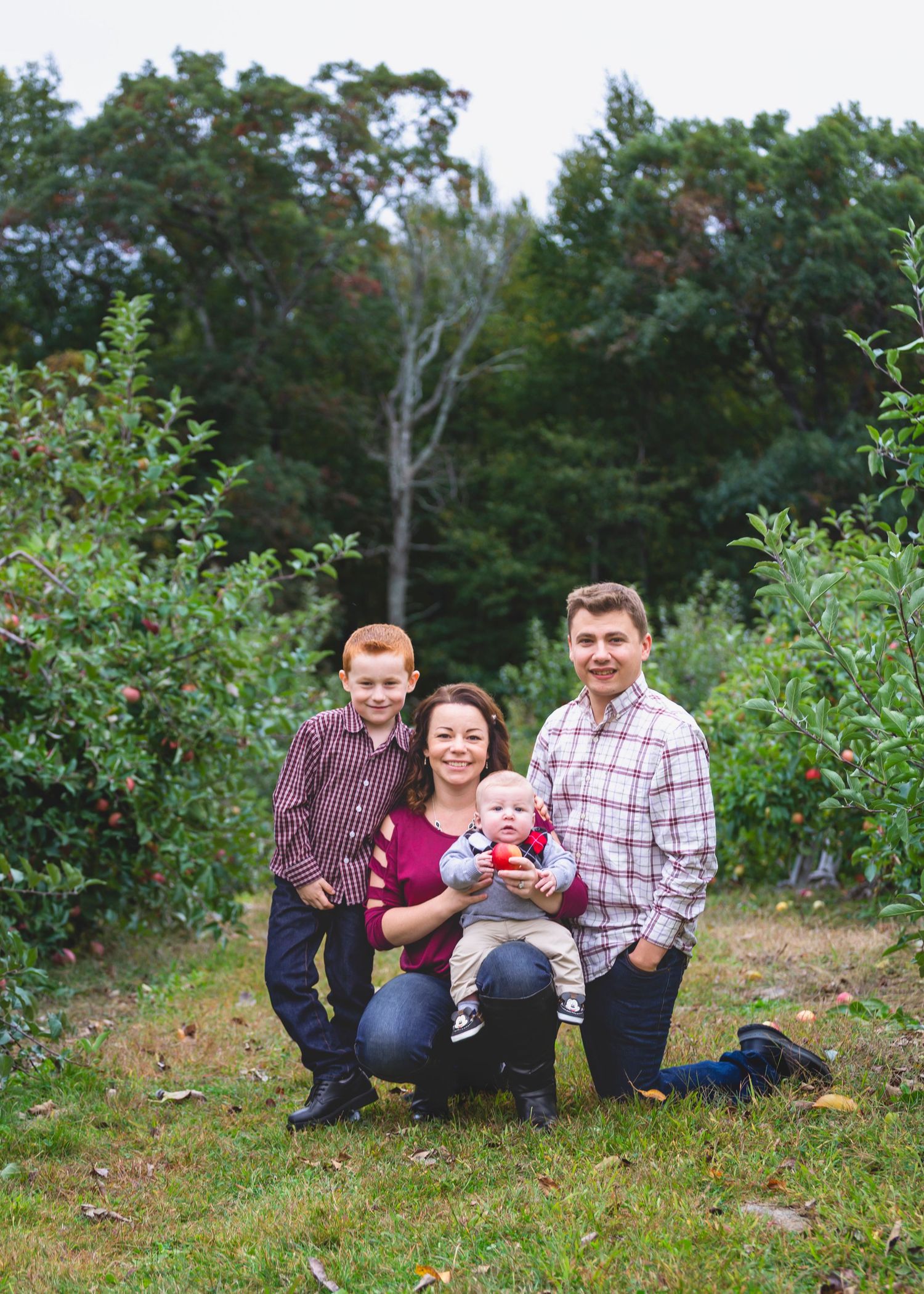 Family of 4 in an apple orchard with matching outfits for fall family portrait