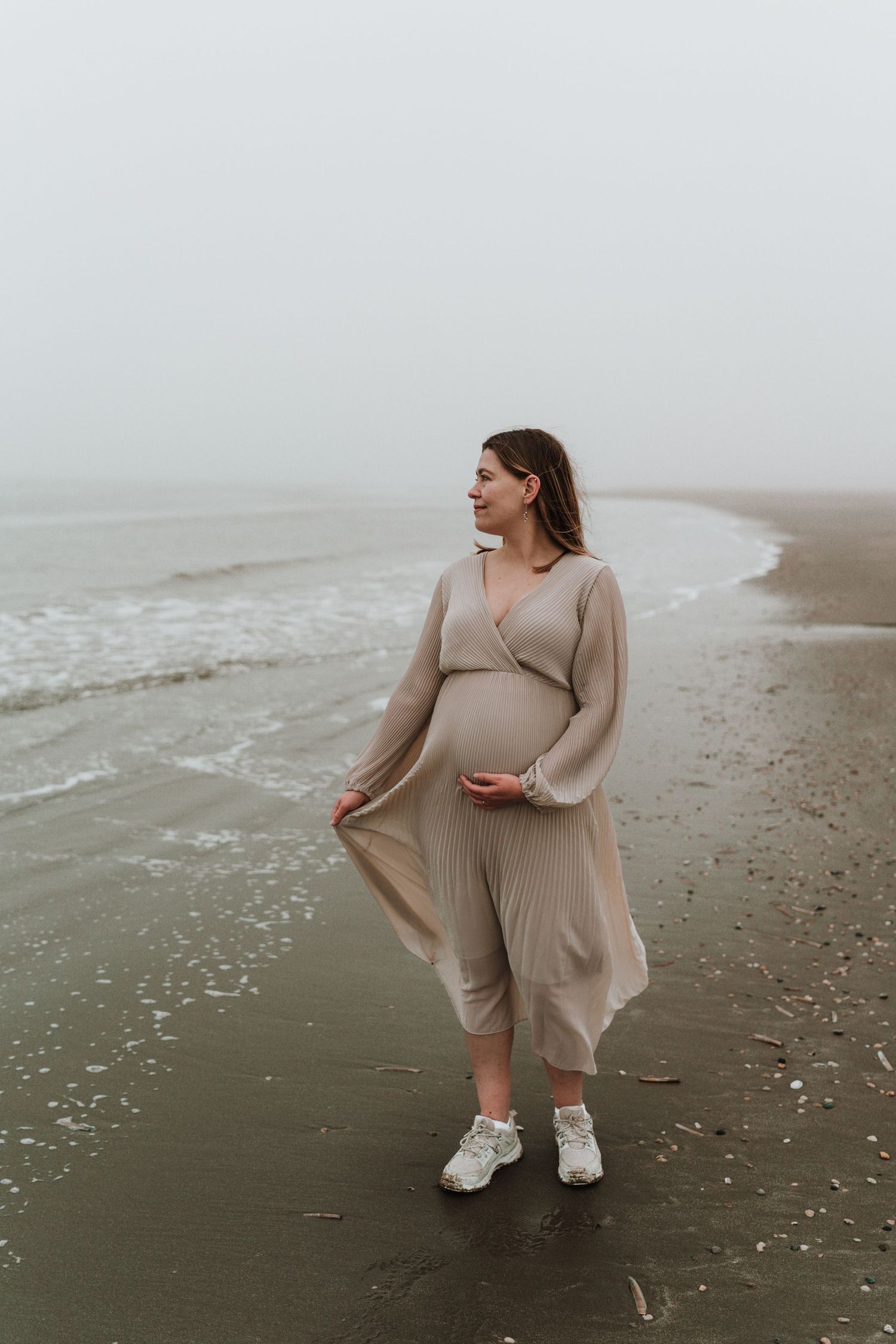 zwangere vrouw op het strand van hoek van holland, kijkt dromerig om zich heen