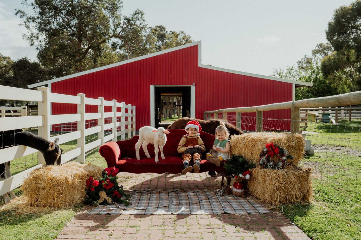 A red barn with white trim stands in a pastoral setting with horses and hay bales visible in the scene.