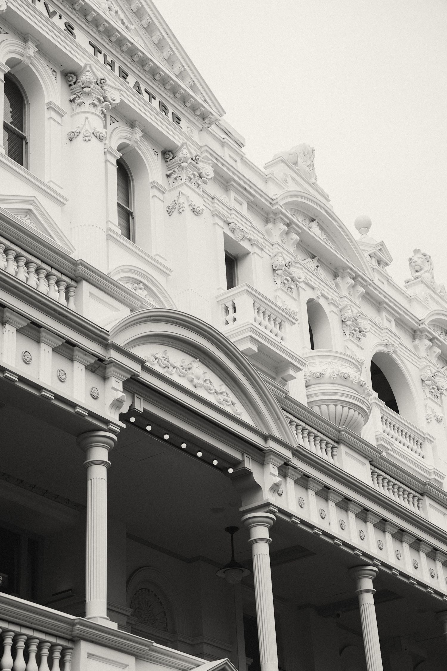 Architectural detail showing white ornate Victorian columns and decorative moldings along a building facade.