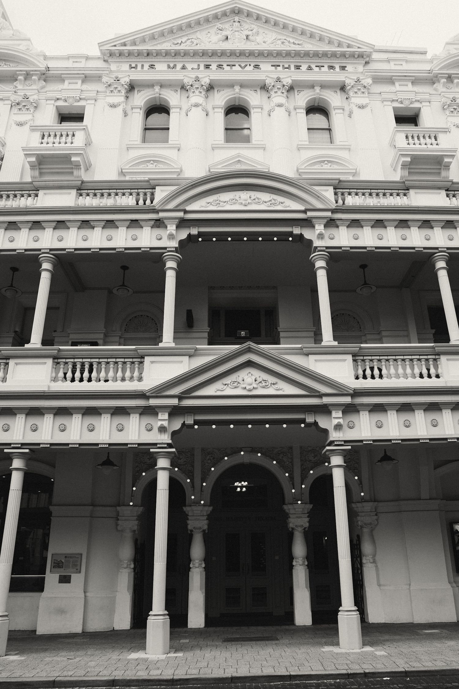 Historic Victorian-era building facade with white columns and ornate architectural details shown in black and white.