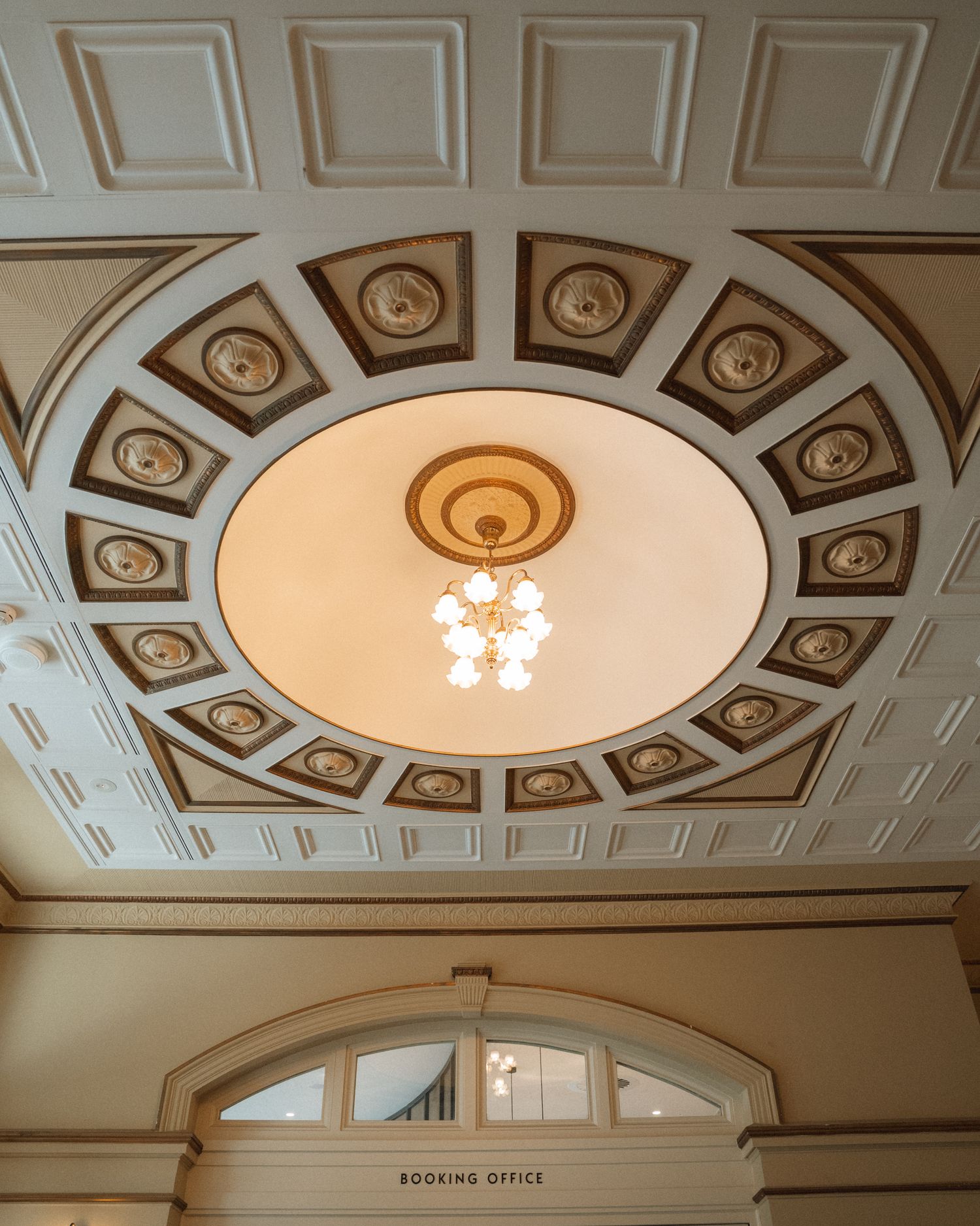 Ornate white ceiling with decorative molding and circular medallions featuring spiral patterns lit by recessed lighting.