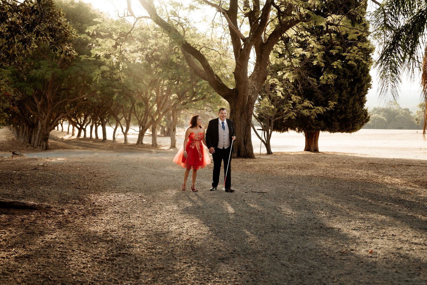 Elegant couple strolling through scenic park during golden hour photography session.