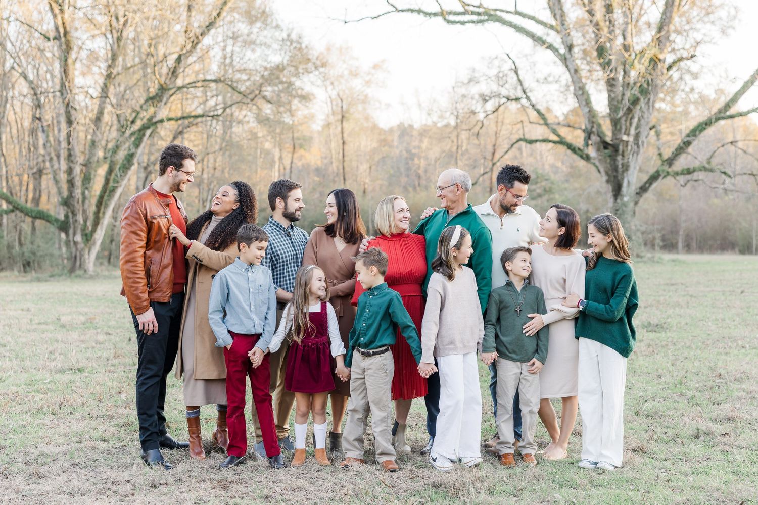 A group of people wearing coordinated fall outfits in teal, burgundy and brown stand together in a scenic outdoor setting.