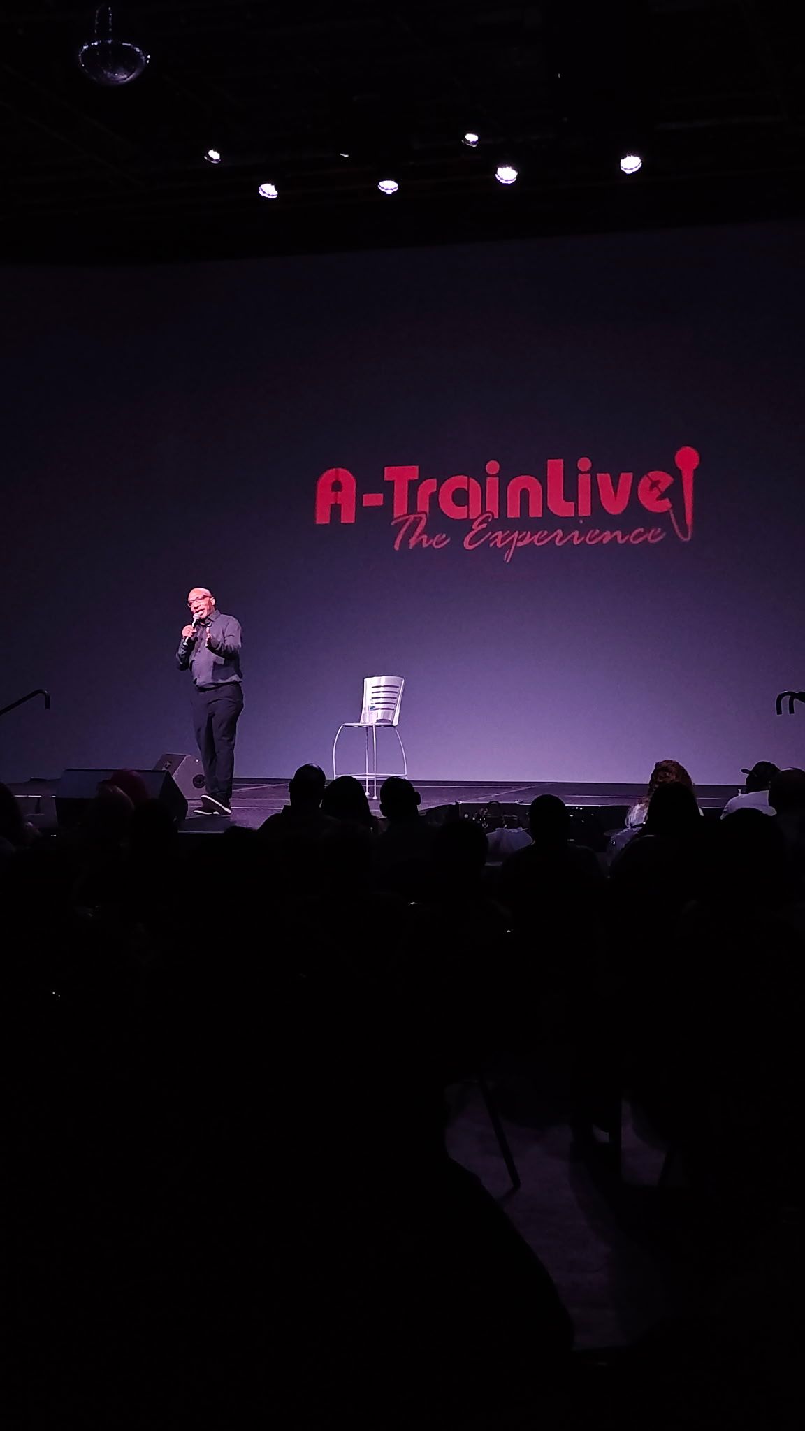 A lone speaker performs on stage before a crowd at A-Train Live The Experience event.