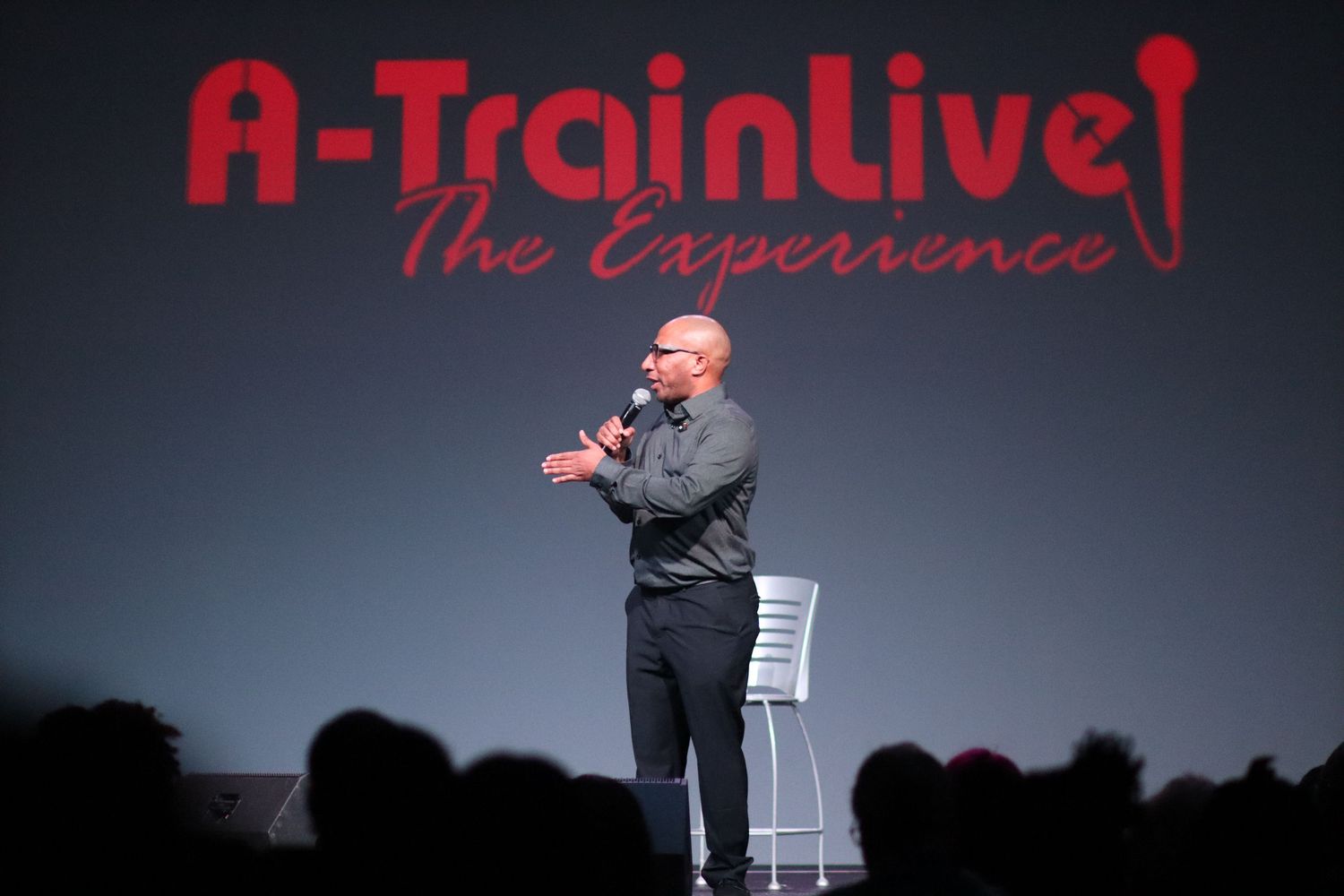 Stand-up comedian performing on stage at A-Train Live The Experience event.
