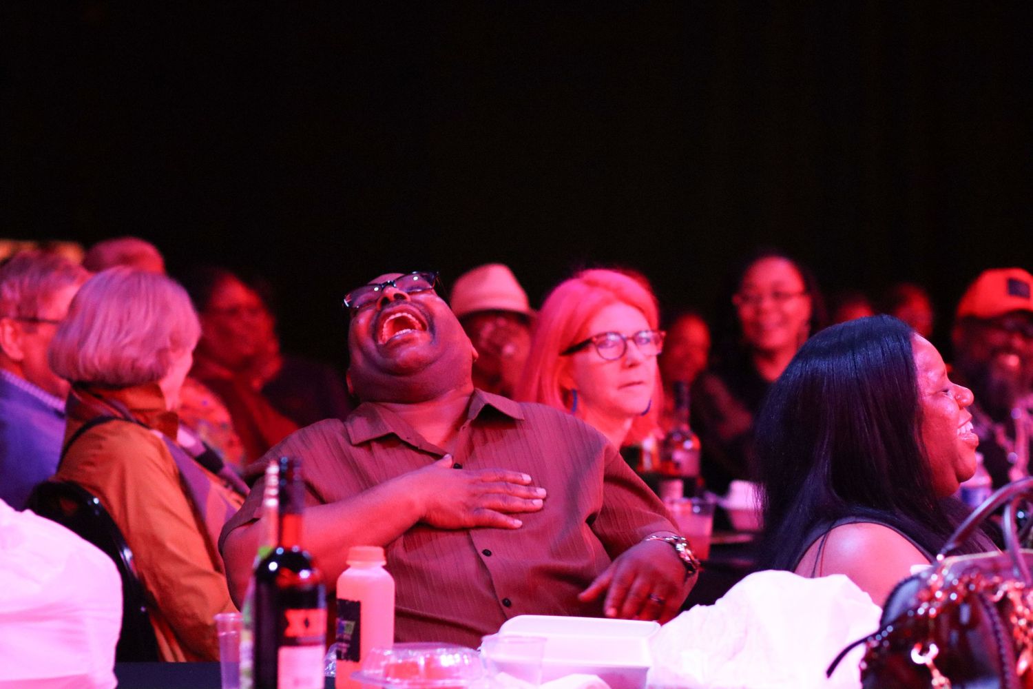 Audience members laughing and enjoying a live comedy show at a dimly lit venue.