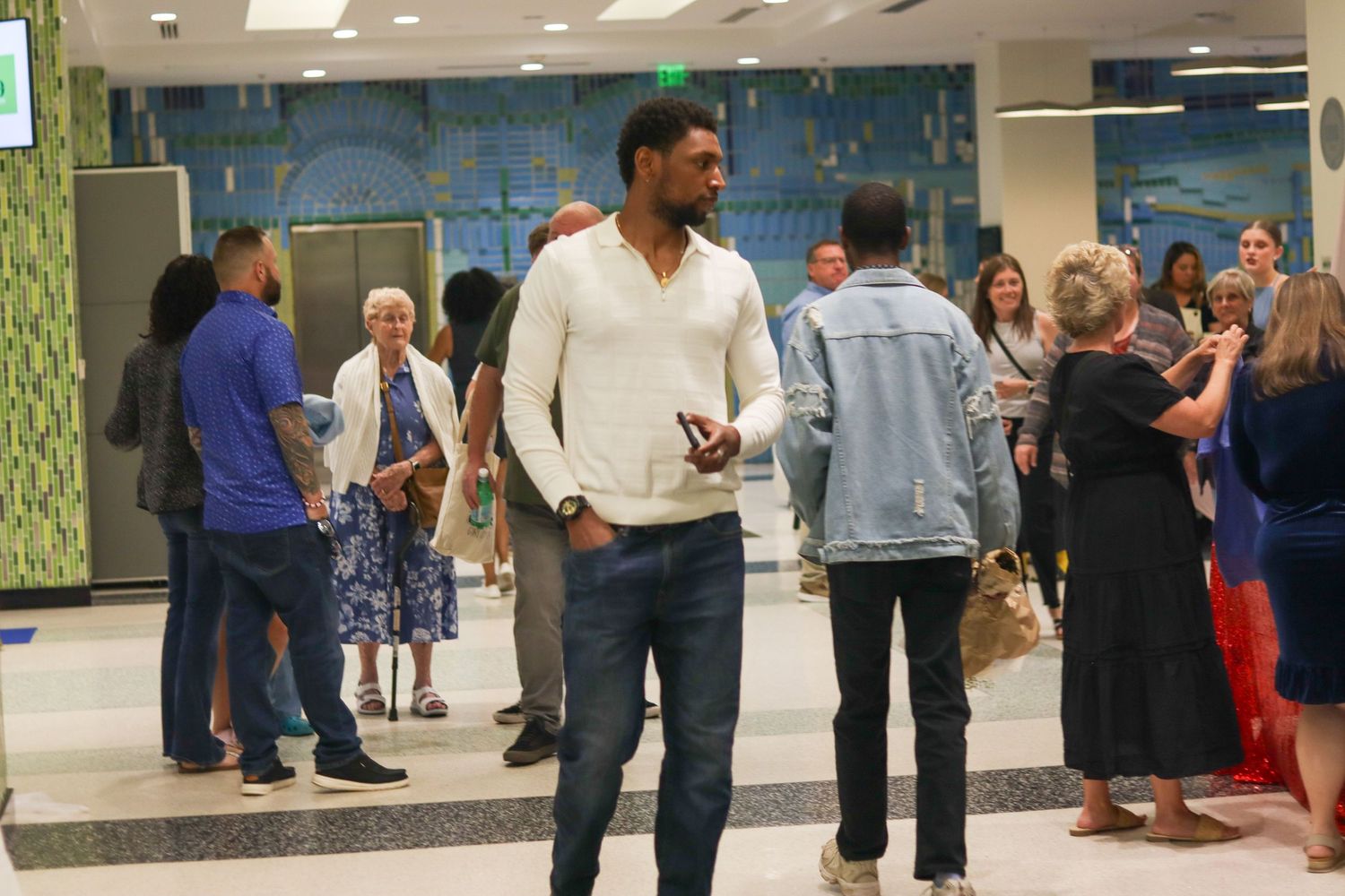 Diverse group of guests mingling in modern lobby during Bridges arts event reception.