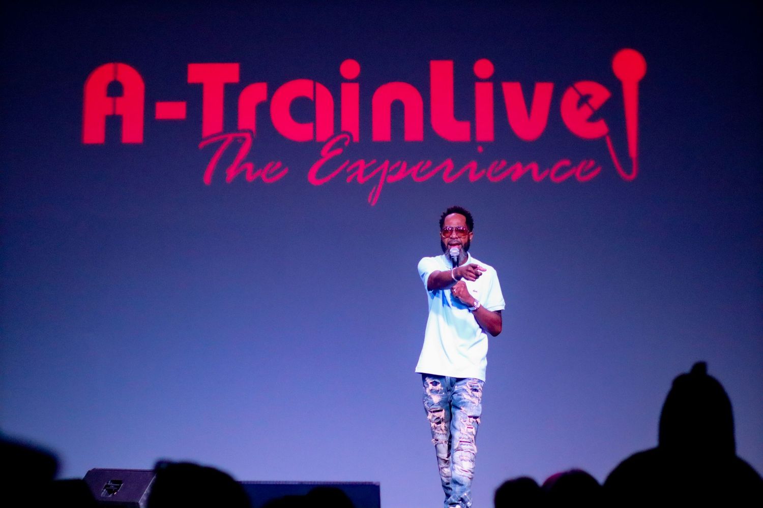 Solo rapper performing on stage under A-Train Live The Experience banner.