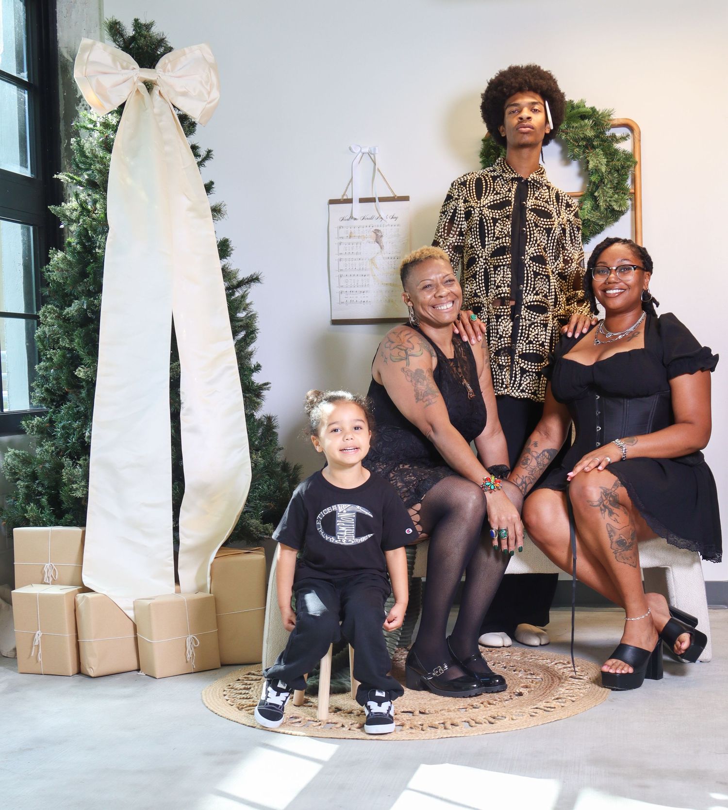 Family of four poses for a festive Christmas photo session with holiday decorations and wrapped gifts.