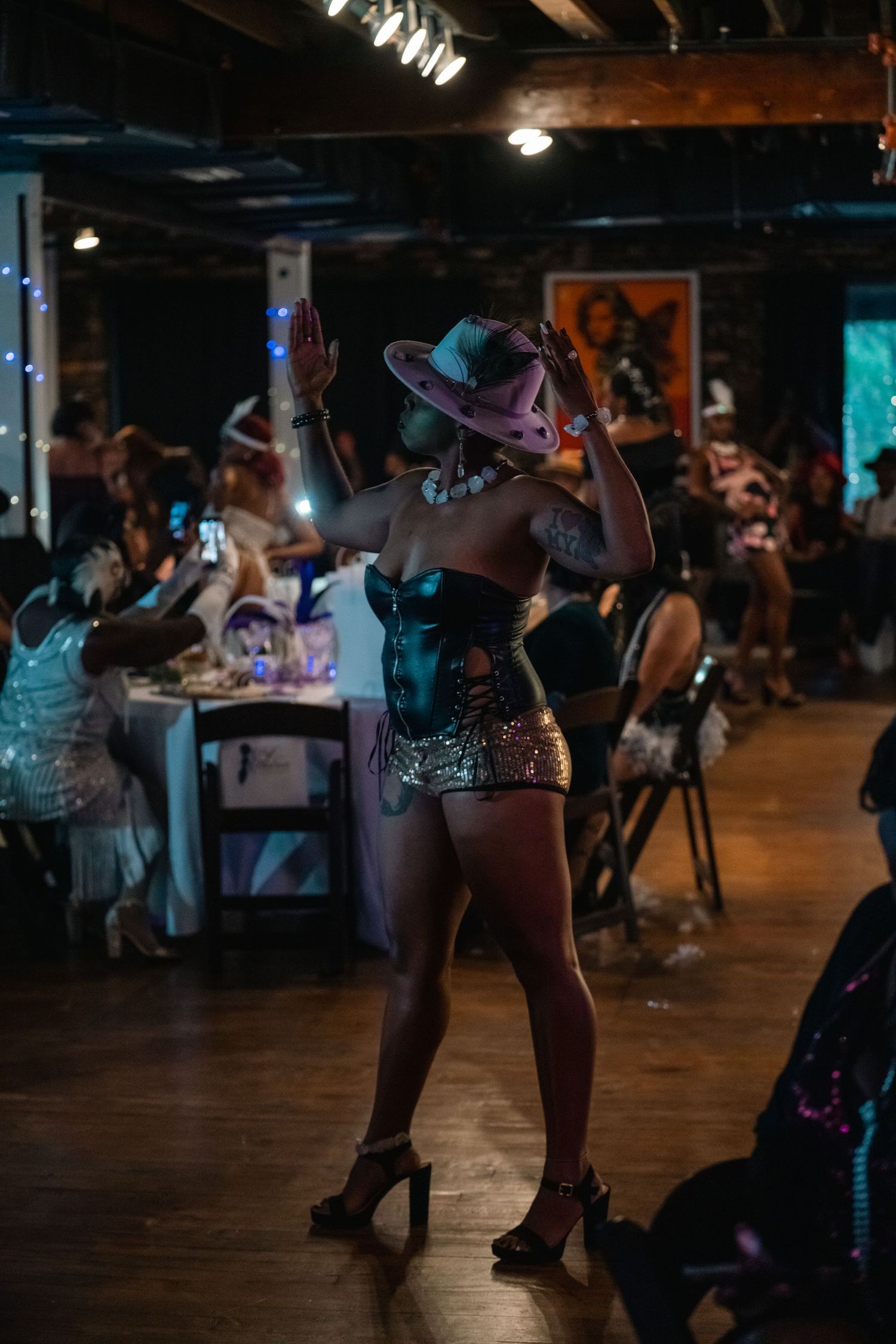 Performer in teal corset and gold skirt dances on stage at nightclub event.