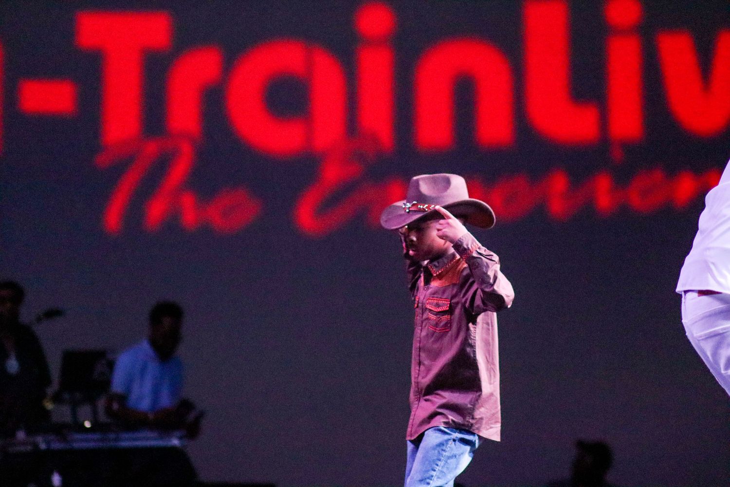 Performer in cowboy hat dancing on stage at A-Train Live The Experience event.