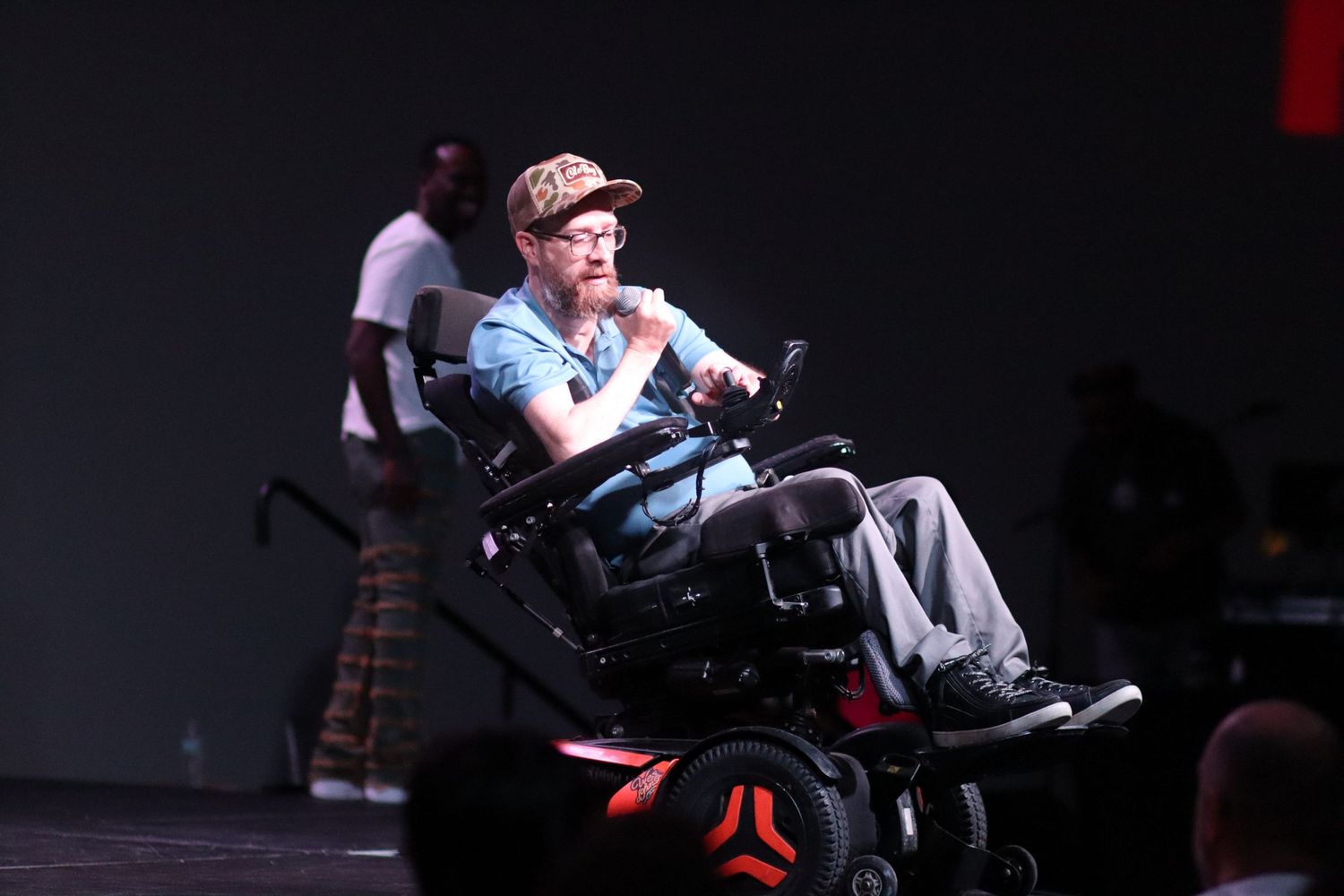 Person in motorized wheelchair performing on stage at a live entertainment event.